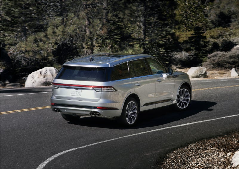 A 2023 Lincoln Aviator® Grand Touring model is shown being driven on a tight turn of a mountain road | Green Lincoln in Greensboro NC