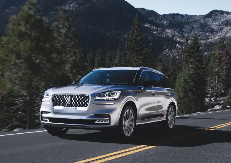 A 2023 Lincoln Aviator® Grand Touring SUV being driven on a winding road to demonstrate the capabilities of all-wheel drive | Green Lincoln in Greensboro NC