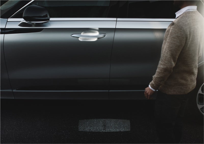 A person approaches a 2023 Lincoln Aviator® Grand Touring SUV as the Lincoln Embrace sequence of welcome lighting illuminates | Green Lincoln in Greensboro NC