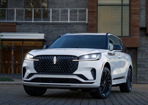 A 2026 Lincoln Aviator® Reserve model is shown with the available Jet Appearance Package parked near a restaurant. | Green Lincoln in Greensboro NC