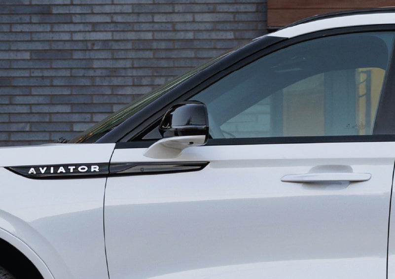 The driver’s side door and fender badging of a white 2026 Lincoln Aviator® SUV are showcased. | Green Lincoln in Greensboro NC