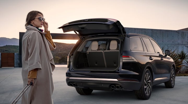 A woman approaches a 2026 Lincoln Aviator® SUV with its rear liftgate open. | Green Lincoln in Greensboro NC