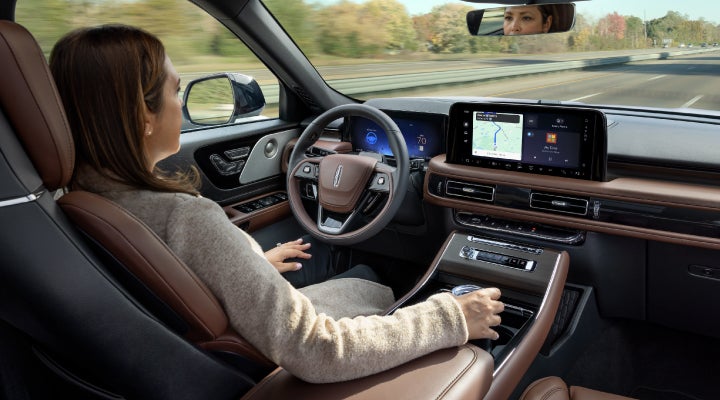A 2026 Lincoln Aviator® SUV is being driven hands-free on a highway near a forest | Green Lincoln in Greensboro NC