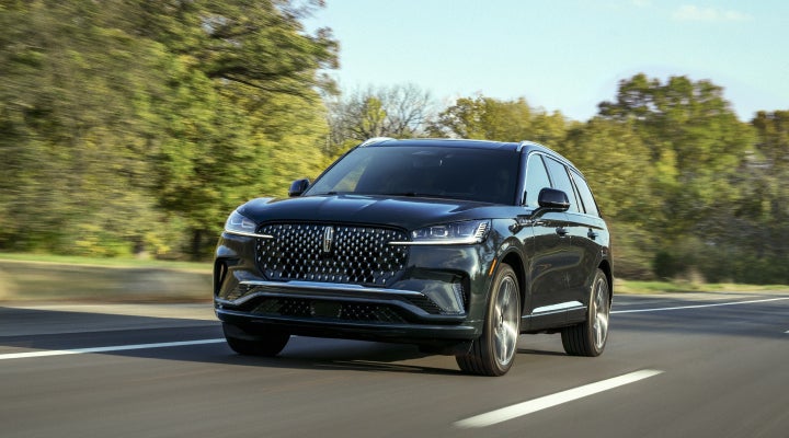 A 2026 Lincoln Black Label™ Aviator® SUV is being driven down a road lined with trees. | Green Lincoln in Greensboro NC