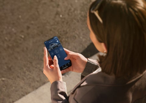 A person is shown interacting with a smartphone to connect to a Lincoln vehicle via the Lincoln Way® app. | Green Lincoln in Greensboro NC
