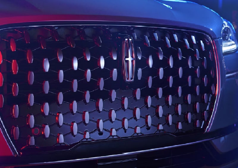 The grille of a 2025 Lincoln Corsair® SUV reflects neon light at night. | Green Lincoln in Greensboro NC