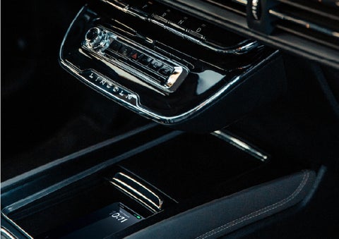 A smartphone rests on the available wireless charging pad in the front center console cubby | Green Lincoln in Greensboro NC