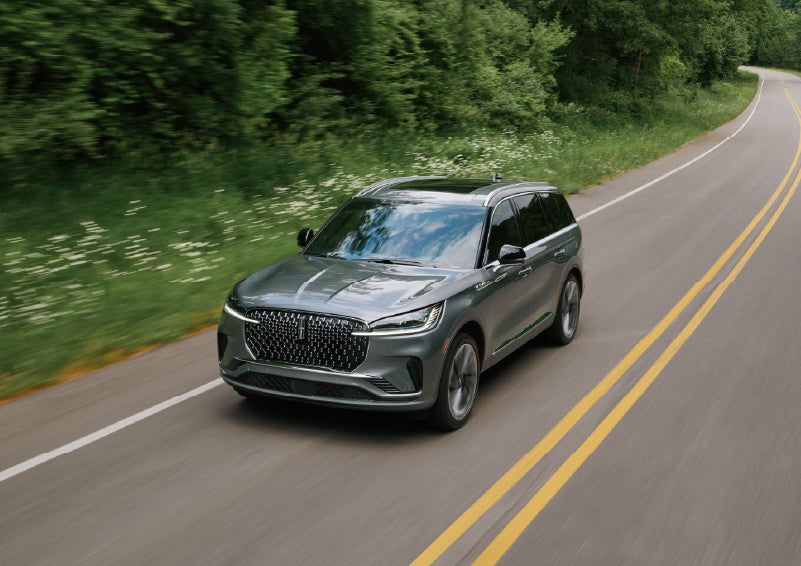 A 2027 Lincoln Aviator® SUV is being driven down a road. | Green Lincoln in Greensboro NC