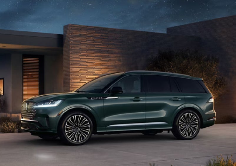 A green 2027 Lincoln Aviator® SUV is parked outside a contemporary home. | Green Lincoln in Greensboro NC
