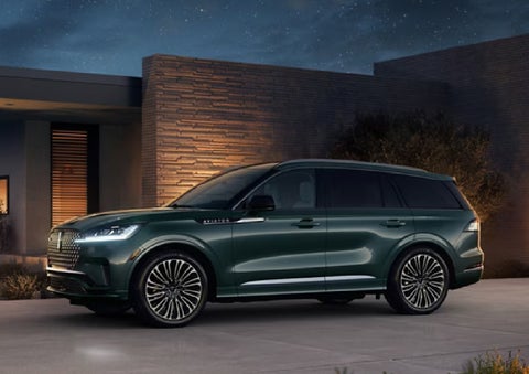A green 2027 Lincoln Aviator® SUV is parked outside a contemporary home. | Green Lincoln in Greensboro NC