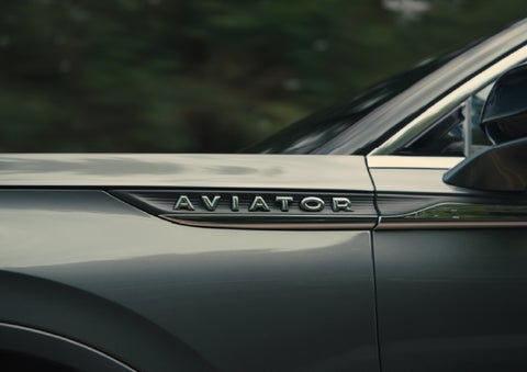 The driver’s side door and fender badging of a gray 2027 Lincoln Aviator® SUV are showcased. | Green Lincoln in Greensboro NC