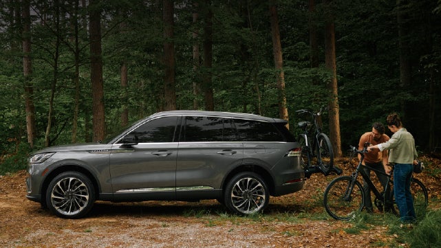 A father and son load e-bikes on a bike rack attached to a 2027 Lincoln Aviator® SUV. | Green Lincoln in Greensboro NC