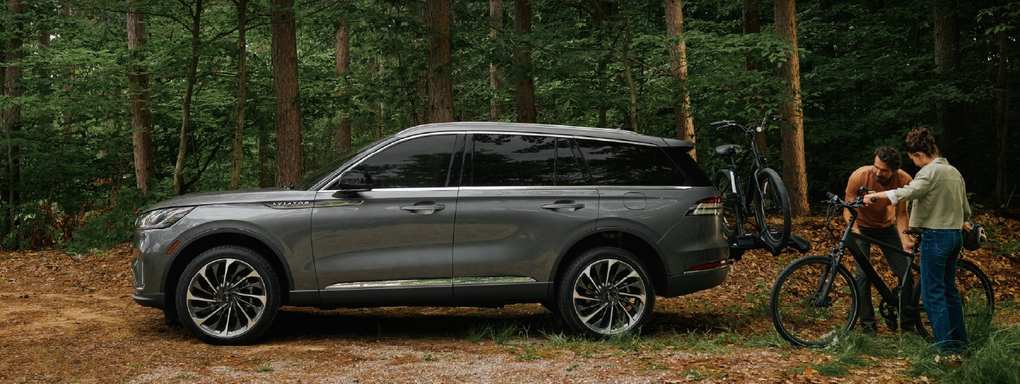 A father and son load e-bikes on a bike rack attached to a 2027 Lincoln Aviator® SUV. | Green Lincoln in Greensboro NC